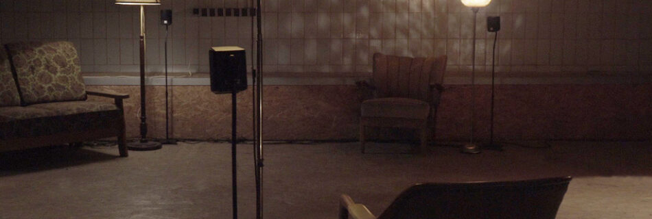 A dark room with various chairs and standard lamps scattered throughout the room.